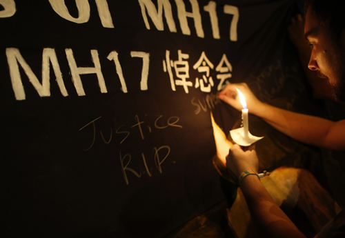 A man writes messages on a banner during a candlelight vigil for victims aboard Malaysia Airlines Flight MH17, which was downed on Thursday over eastern Ukraine, near Chinatown in Kuala Lumpur July 20, 2014. The downing of the airliner with the loss of nearly 300 lives has sharply escalated the crisis in Ukraine, and may mark a pivotal moment in international efforts to resolve a situation in which separatists in the Russian-speaking east have been fighting government forces since protesters in Kiev forced out a pro-Moscow president and Russia annexed Crimea. REUTERS/Edgar Su (MALAYSIA - Tags: TRANSPORT DISASTER POLITICS)